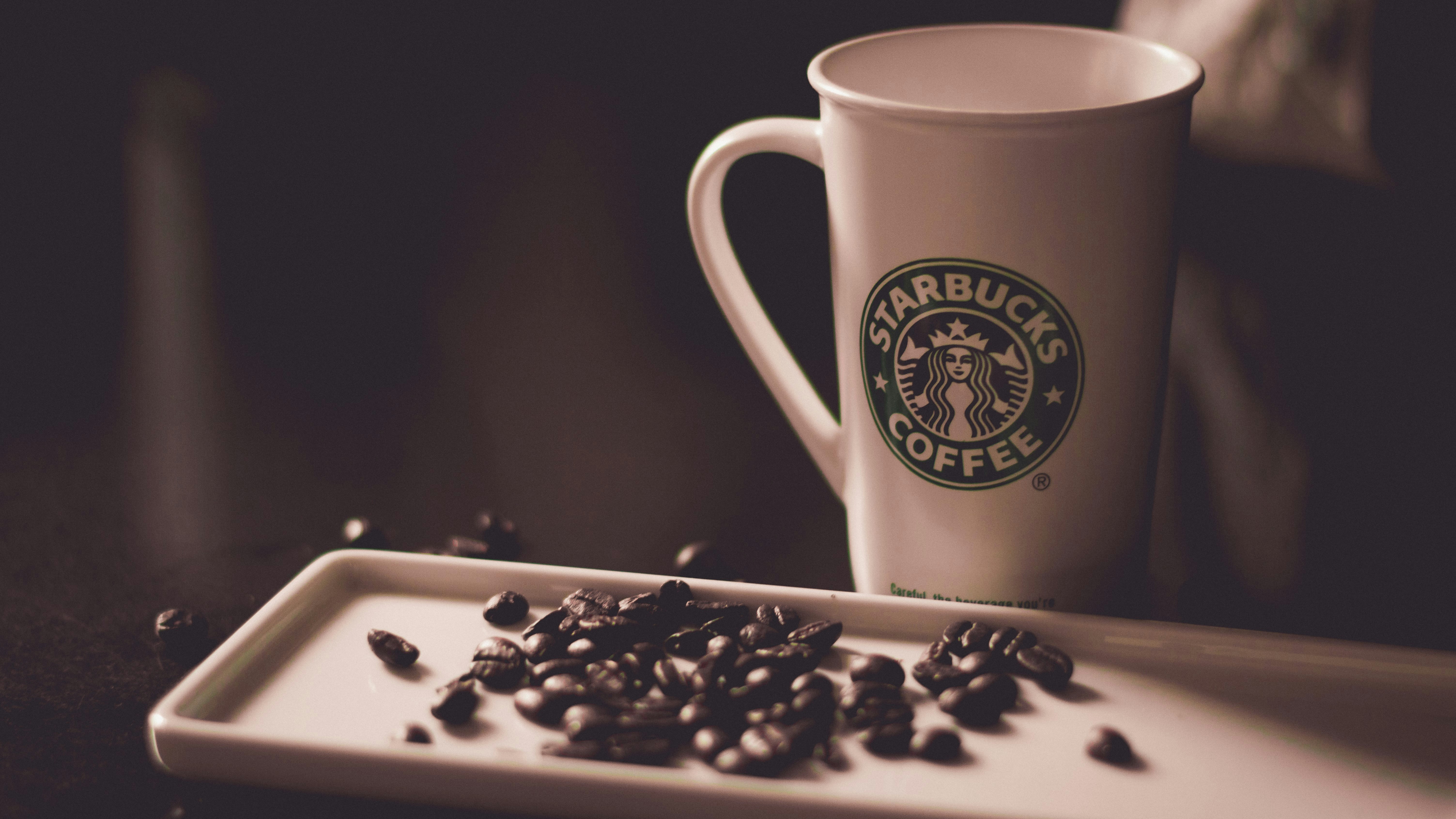 coffee beans beside Starbucks coffee mug